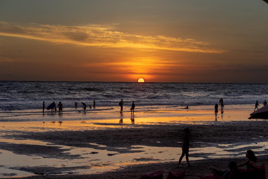 Sunset at Beach with surfers entering the water