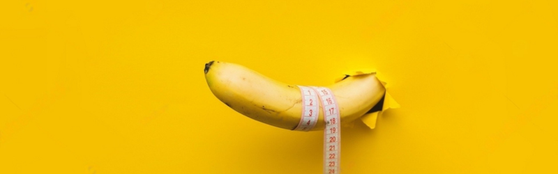 A banana with a tape measure wrapped around it appears through a torn hole in yellow paper