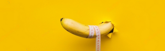 A banana with a tape measure wrapped around it appears through a torn hole in yellow paper