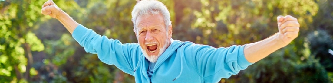 Middle aged man in athletic wear celebrating outdoors with trees in the background