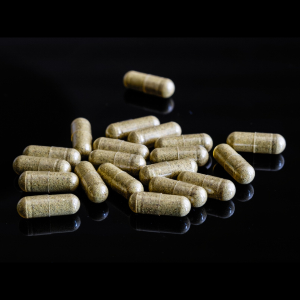 Herbal Mojo for Guys supplement capsules on a reflective black surface
