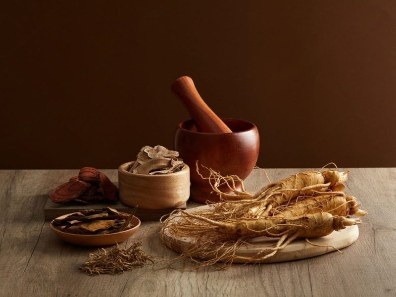 Chinese herbal medicine ingredients including ginseng root and dried herbs in a wooden bowl